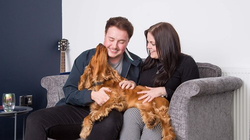 Couple sat on the sofa with their dog