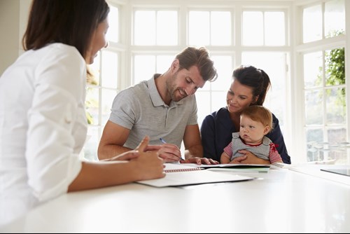 Family with young baby sat signing forms with sales representative.