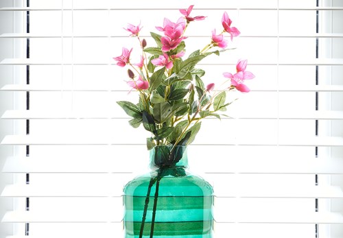 Pink flowers in a green vase infront of a window.