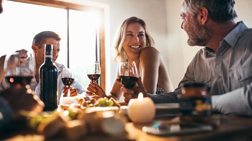 Group of people laughing and enjoying time together whilst drinking wine.